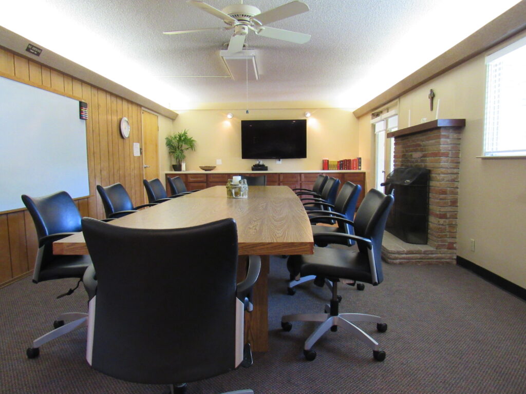 Raine meeting room: a board room style room with long table and chairs and TV screen and fireplace