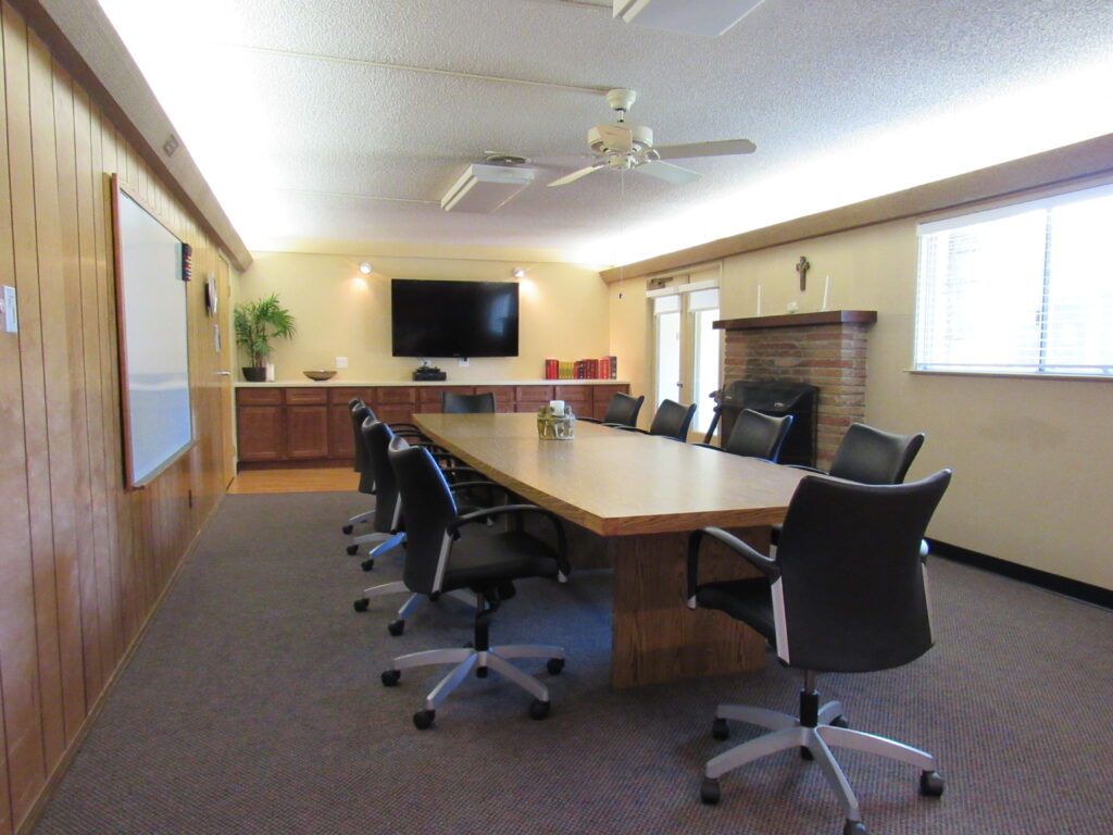 Raine meeting room: a board room style room with long table and chairs and TV screen and fireplace