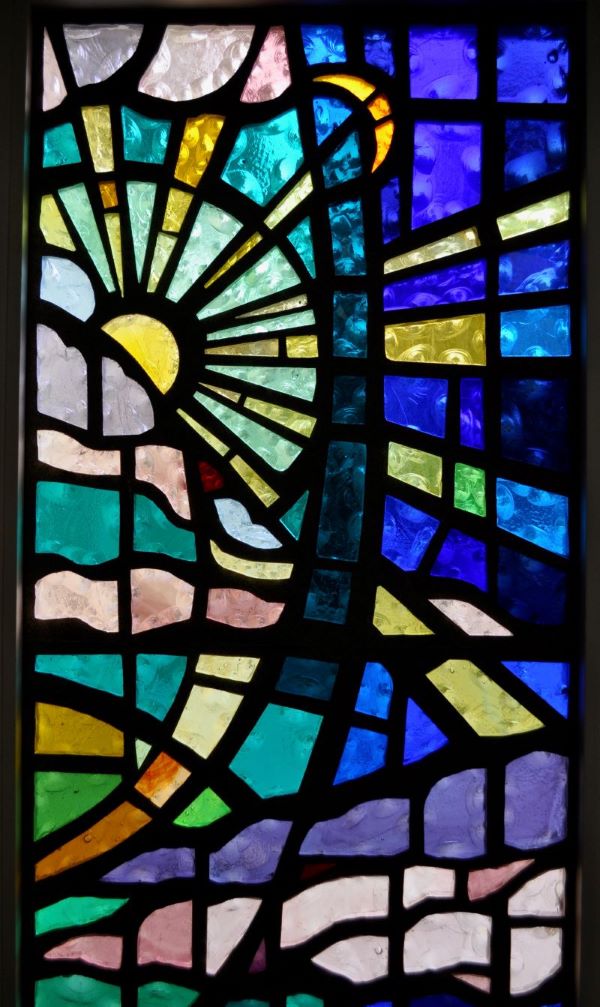 Stained glass window of the sun, moon, water and land representative of the Genesis creation story