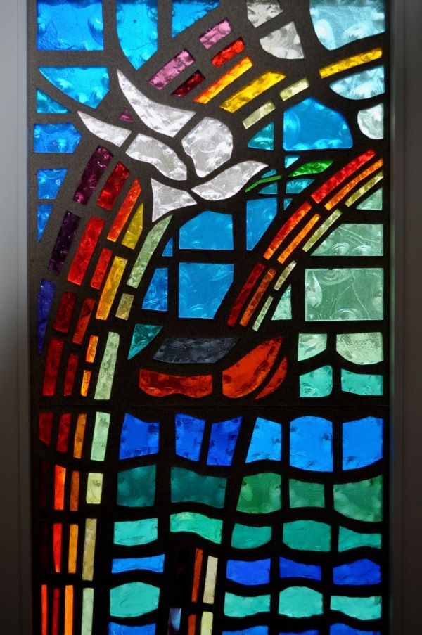 Stained glass window of a dove and a rainbow representing the Genesis story of Noah's Ark