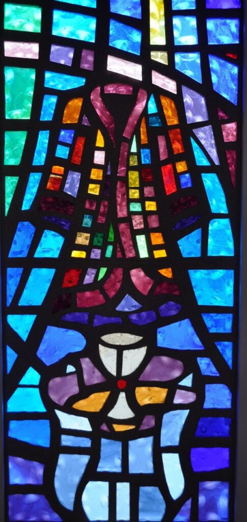 Stained glass window of a coat with many colors representing the Genesis story of Joseph's Coat of Many Colors