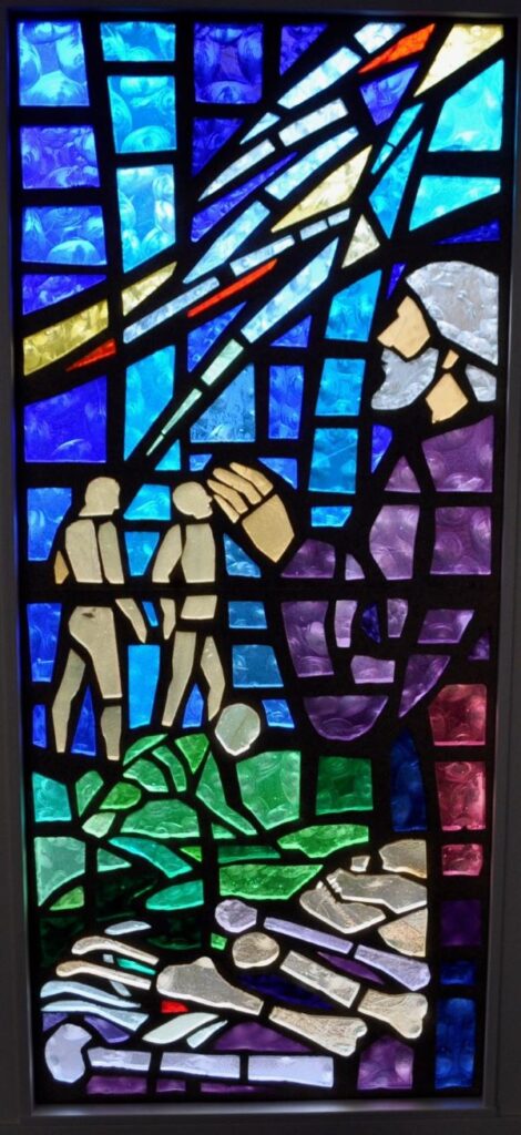 Stained glass window of bones turning into people representative of the Ezekiel story of the Valley of Dry Bones