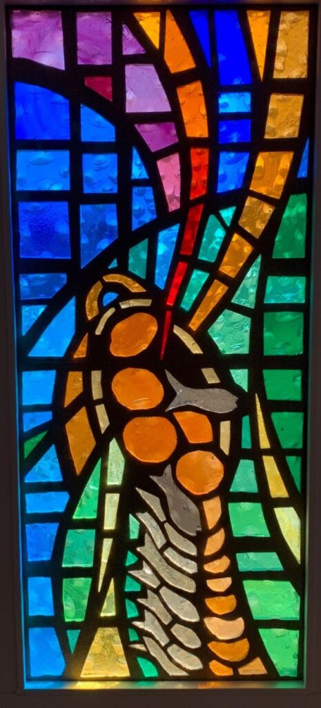Stained glass window of a basket overflowing with fish and loaves of bread representative of the Matthew, Mark and Luke stories of the Miracle of the Loaves and Fishes