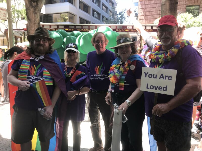 Parishioners from WCUMC at a Pride event. Dave holds a sign that says " You are Loved"