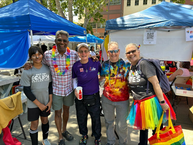A group of church members wearing lays and posing for a picture with vibrant colors at a pride event in Concord, CA